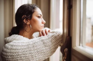 Chica mirando por la ventana con gesto melancólico